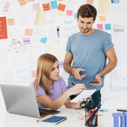 young-employees-analyzing-writings-notebook-near-workplace